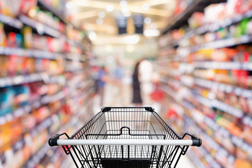 Einkaufswagen zwischen Regalen in einem Supermarkt